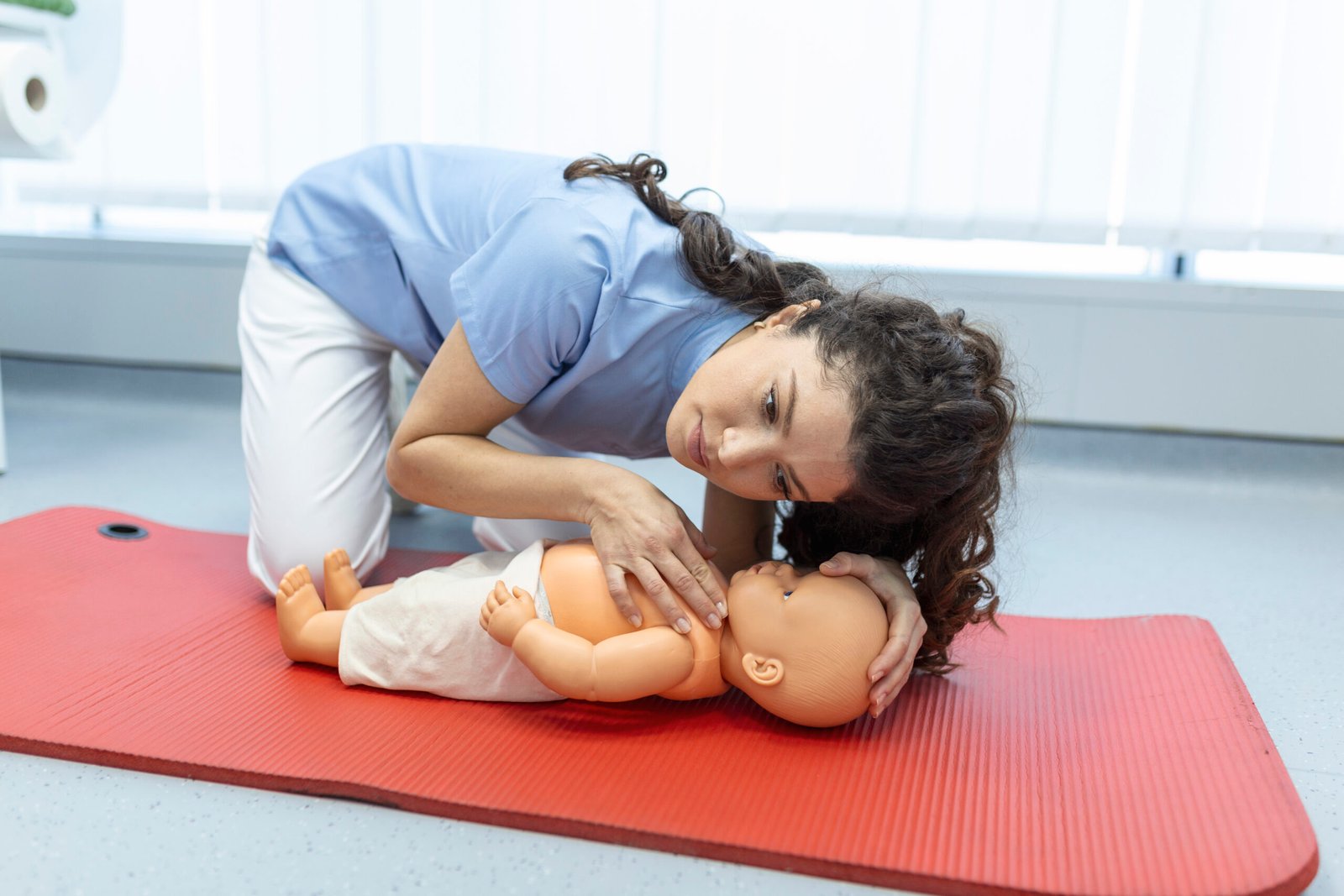Woman performing CPR on baby training doll with one hand compression. First Aid Training - Cardiopulmonary resuscitation. First aid course on cpr dummy